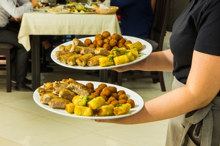 Restaurant catering services. Waitress with food dish serving banquet tableの写真素材