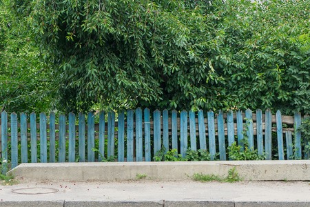 Old wooden blue fence in village with orchard behindの写真素材