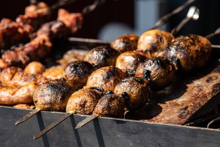 Grilled baked potatoes on skewers . street food festival.