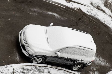 A car covered in the first snow parked near a multi-storey. Top view. . winter dayの写真素材