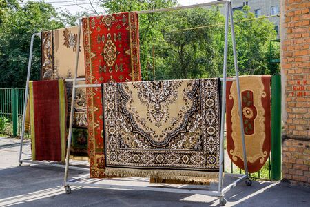 Different carpets hanging on rack outdoors. Professional carpet cleaning and drying.