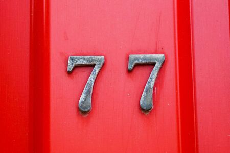 house number 77 on iron red background, seventy-seven.の写真素材