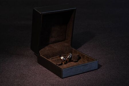 Two gold wedding rings in a brown box on a dark background.の写真素材