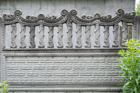 Grey decorative concrete fence with balustrades near the house