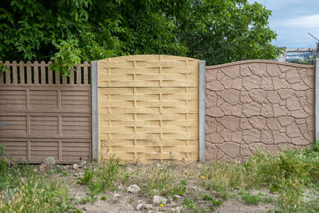 Multicolored concrete slabs of the fence against the background of greenery in the garden.の写真素材