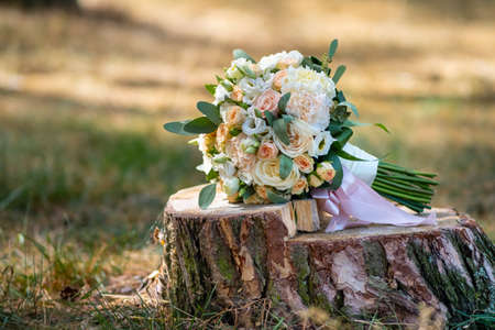 Beautiful bouquet of roses in pink tones lies on a tree stump. Wedding decorの写真素材