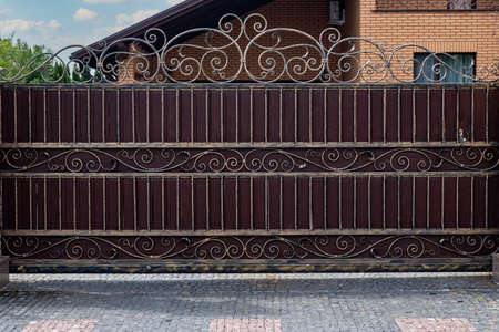 Modern strong decorative gates with wrought iron elements near a residential building.