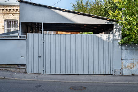 The gate in front of the house is made of gray corrugated metal.