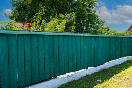 The old weathered wooden green fence near residential homes.の写真素材