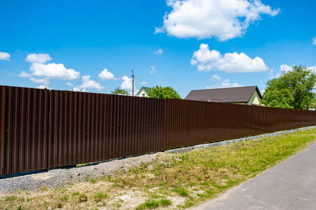 Brown metal corrugated fence against the sky. Texture of profiled metal.の写真素材