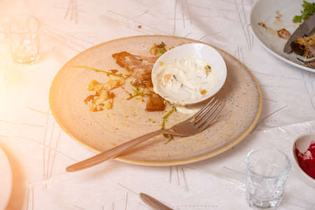 The leftover food and dirty dishes on the restaurant table. Scraps left over after the party.