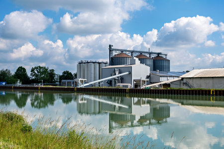 Agro-processing facility for processing, drying, cleaning and storing agricultural products, flour, cereals and grain. Barn elevator on the bank of the canal.の写真素材