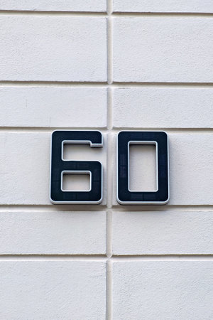 Black and white sign on white brick wall that says 60 on it in Germany
