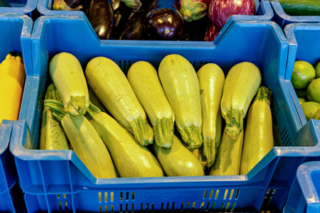 Bunch of zucchini sitting inside of blue crate next to apple.の写真素材