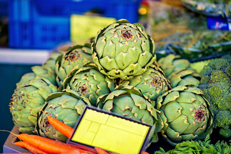 Bunch of artichokes and carrots for sale at market.の写真素材