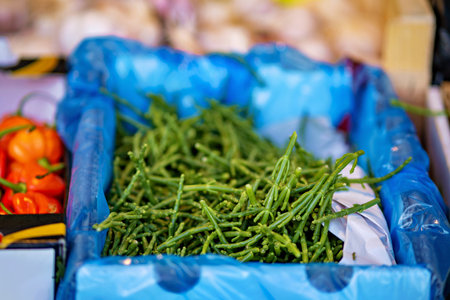 Bunch of green beans and tomatoes in blue container on table.の写真素材