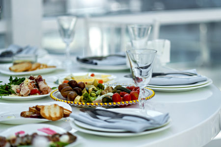 Table topped with plates of food next to glasses of water and plates of food.