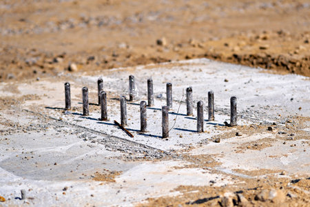 This image shows a collection of metal rods or pipes embedded in a concrete or cement surfaceの写真素材
