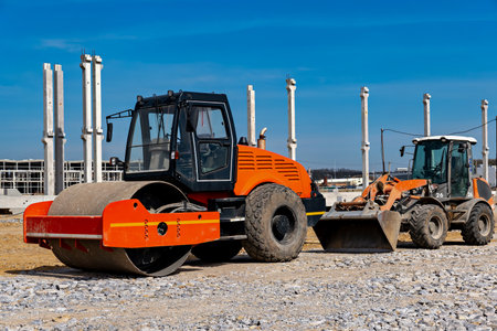 This image shows two pieces of heavy machinery parked on a gravel surfaceの写真素材