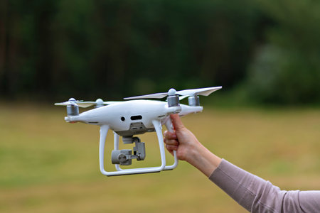 A person is holding a white drone with a camera attached to itの写真素材