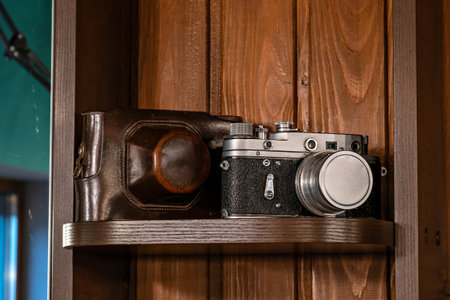 A vintage camera and a leather case on a wooden shelf