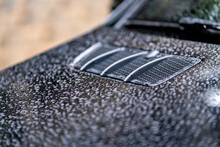 A close-up photograph of a car's grille with a water droplet pattern on it