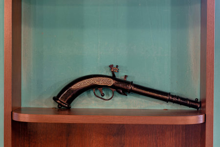A black gun with a decorative handle is displayed in a wooden caseの写真素材