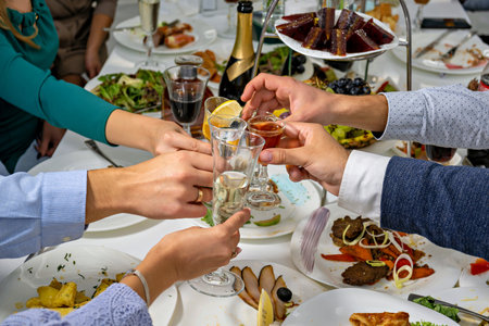 A group of people are toasting with champagne glasses at a table filled with food and drinks