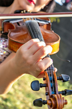 A close-up of a person's hand playing a violin..