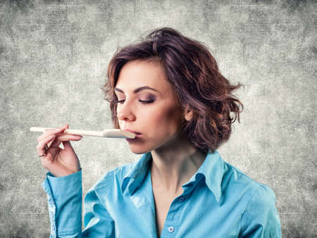 Photo of the girl with a spoon near a mouthの写真素材