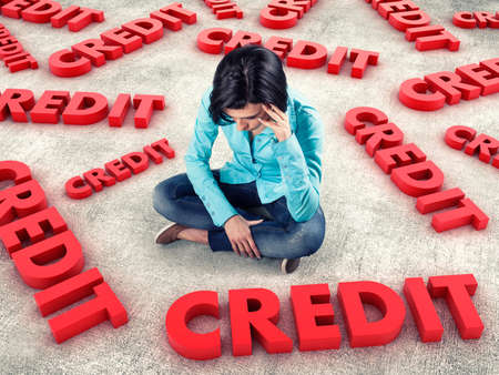 Sad girl sits among many red creditsの写真素材