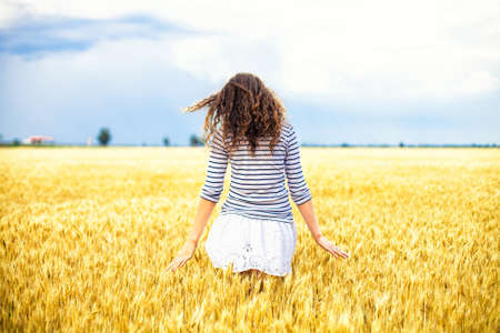 The beautiful girl is on a wheaten field