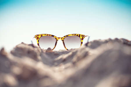 Sun glasses lie on a beach near the seaの写真素材