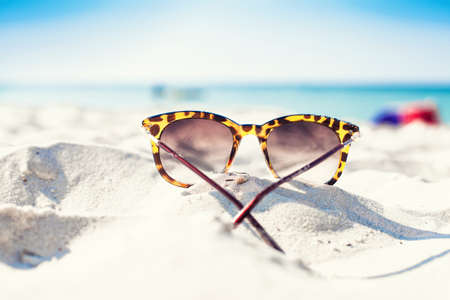 Sun glasses lie on a beach near the seaの写真素材