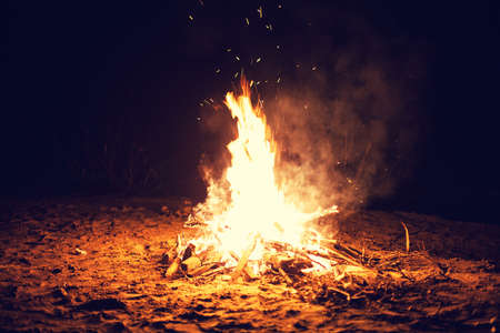 The bright big bonfire burns on a beach at nightの写真素材
