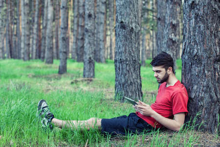 The boy sits under a tree and reads the bookの写真素材