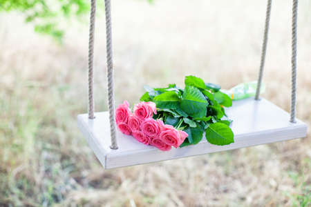 Beautiful pink flowers lying on a swingの写真素材