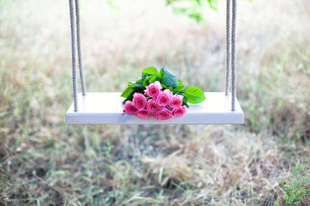 Beautiful pink flowers lying on a swingの写真素材