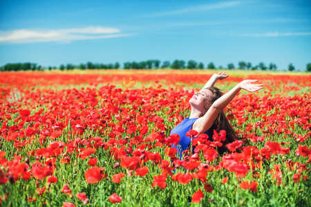 The beautiful girl on a red field with poppiesの写真素材