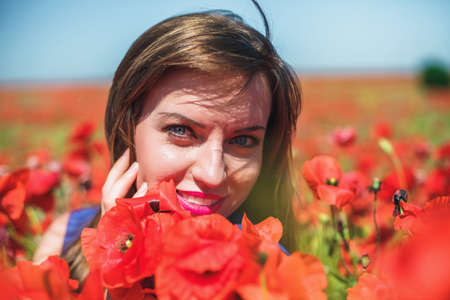 The beautiful girl on a red field with poppiesの写真素材