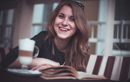 Beautiful girl with cup latte and a bookの写真素材