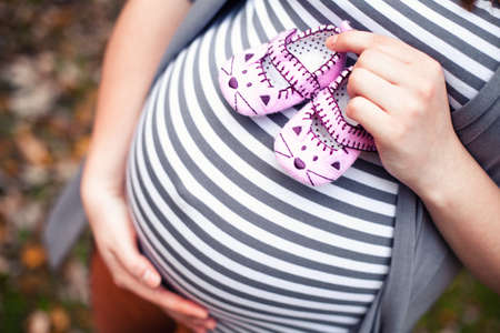 Beautiful pregnant woman with a big belly and shoesの写真素材