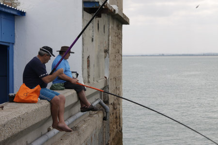 Fishermen are fishing in the harbor of the seaport of Cadiz.のeditorial素材