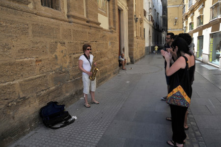 An unknown woman plays the saxophone on the old street of the city of Cadiz.のeditorial素材
