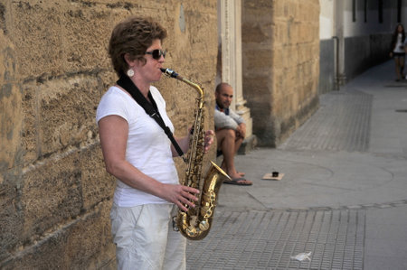 An unknown woman plays the saxophone on the old street of the city of Cadiz.のeditorial素材