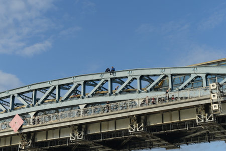 Young people are sitting on the arch of Pushkin (Andreevsky) pedestrian bridge on the Moskva River.