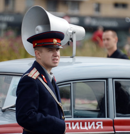 A reconstructor in the Soviet uniform of a police officer at the Moskvich-401 car at an exhibition of old transport.のeditorial素材