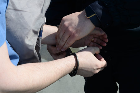Buttoning the police steel handcuffs on the hands of menのeditorial素材