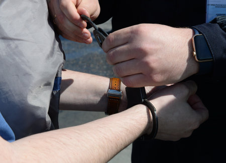 Buttoning the police steel handcuffs on the hands of menのeditorial素材