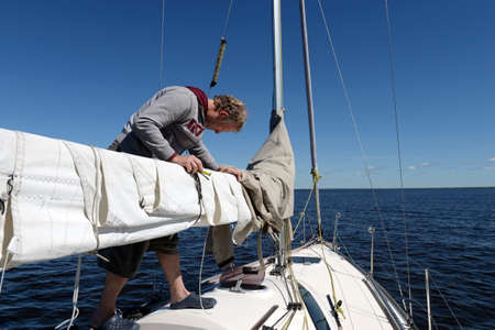 Unknown yachtsman makes minor repairs to the sail on a yacht